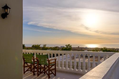 a balcony with two chairs and a view of the ocean at Kaminia Holiday Homes in Éxo Goniá