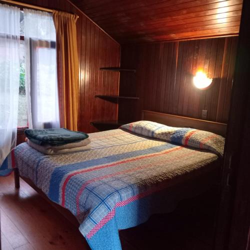 a bedroom with a bed with a blanket on it at Posada Kalku in El Tabo