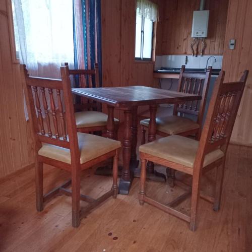 a wooden table and chairs in a kitchen at Posada Kalku in El Tabo