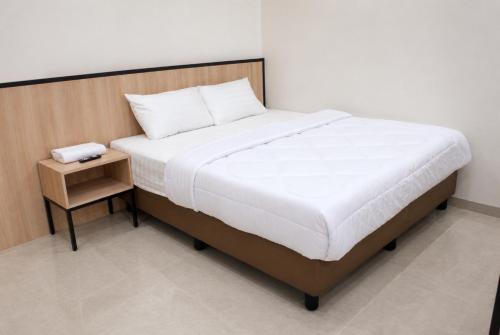 a bed with a wooden headboard and a night stand at Djuragan Kamar Labuhan in Semarang