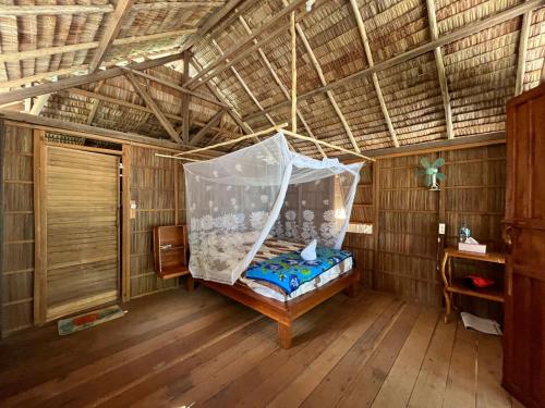 a bed in a room with a net at Kemmi Homestay Raja Ampat in Merpati