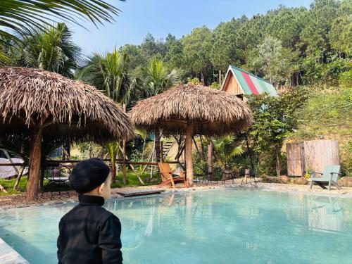 a young boy is looking at a swimming pool at BIRD HOUSE resort in Hữu Biêt