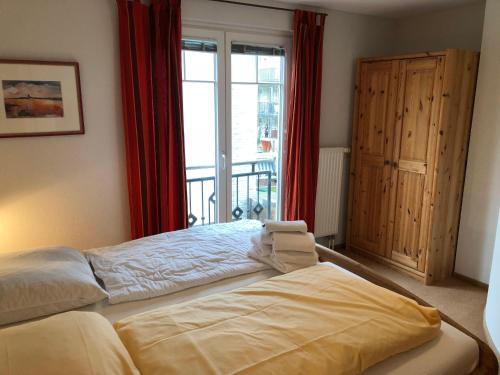 a bedroom with a bed with red curtains and a window at Ferienwohnung-Silvie-8 in Westerland