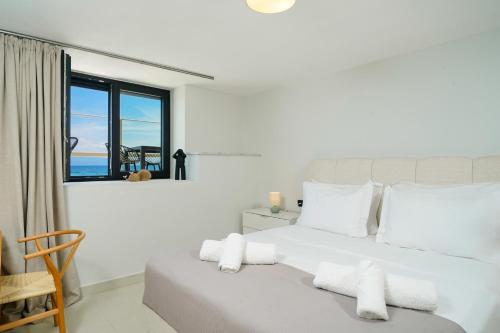 a bedroom with a white bed with a view of the ocean at Elysian Seaside Suite in Skala Kallirachis