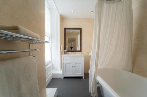 a bathroom with a tub and a sink and a mirror at Old Swan Hotel in Harrogate