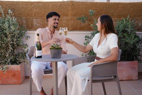 a man and woman sitting at a table with glasses of wine at Bytra Boutique Hotel - Adults Only in Petra