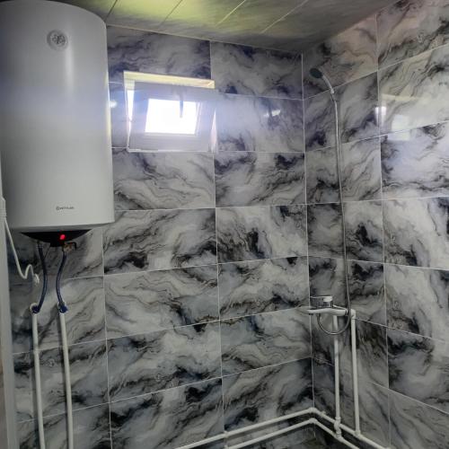 a bathroom with a marble tile wall and a shower at Gugas cottage and guest house in Lakhiri in Lakhiri