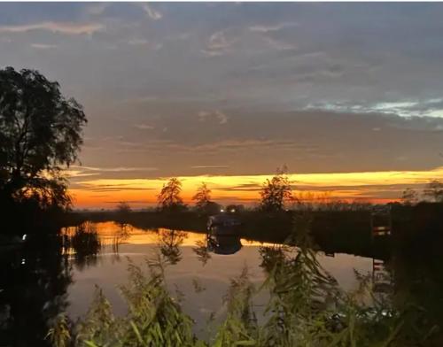a sunset over a lake with a boat in the water at Wetterwillefriesland in Wommels