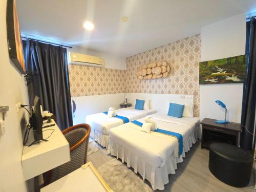 a hotel room with three beds and a desk at The Nice Patong Hotel in Patong Beach