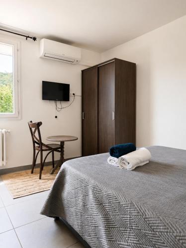 a bedroom with a bed and a tv and a table at Hôtel Restaurant le Mistral in Peipin