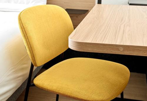 a yellow chair sitting next to a table at B&B HOTEL Magnanville in Magnanville