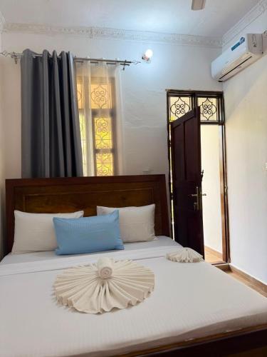 a white bed with a wooden headboard and a window at Ebruli Guest House in Nungwi