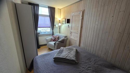 a bedroom with a bed and a chair and a window at Ferienwohnung am Müritzstrand in Waren
