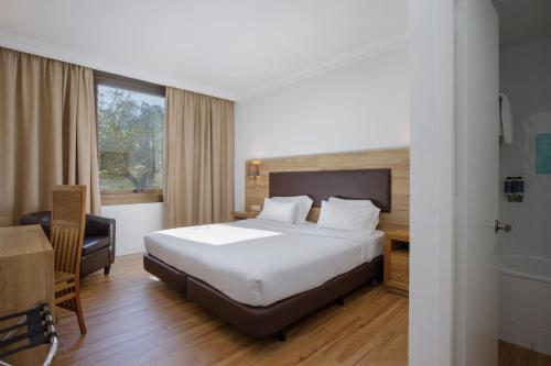 a bedroom with a bed and a desk and a window at Hotel Eden Park by Brava Hoteles in Riudellots de la Selva