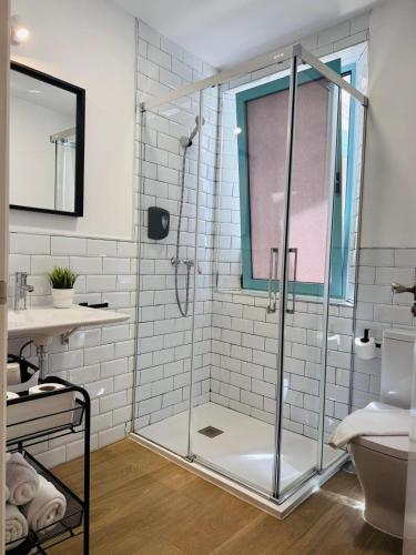 a bathroom with a glass shower with a sink and a toilet at Alegoría Coliving Experience in Seville