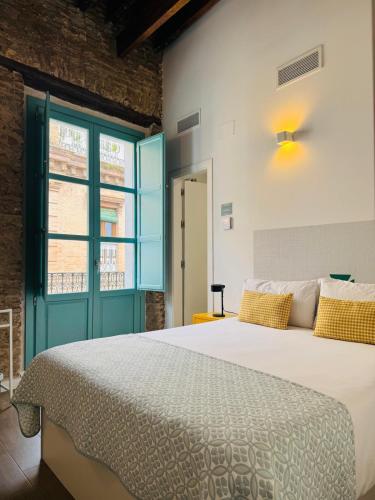 a bedroom with a large white bed with yellow pillows at Alegoría Coliving Experience in Seville
