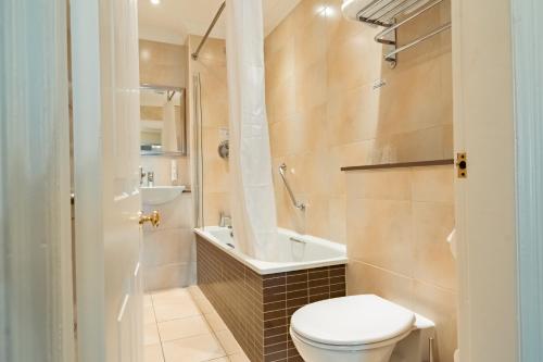 a bathroom with a toilet and a tub and a sink at Farington Lodge Hotel in Preston