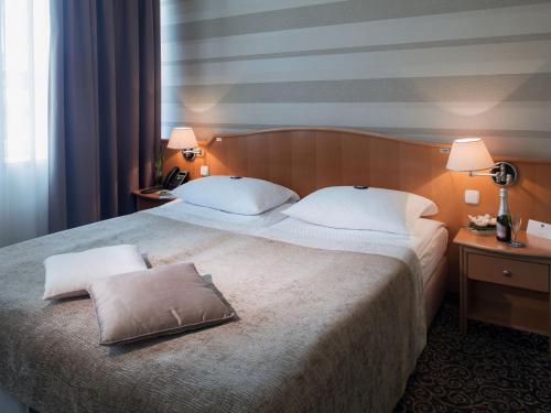 ein Hotelzimmer mit einem großen Bett und zwei Kissen in der Unterkunft Hotel Paka in Velenje