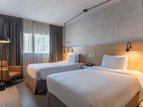a hotel room with two beds and a chair at Novotel Bogota Parque 93 in Bogotá