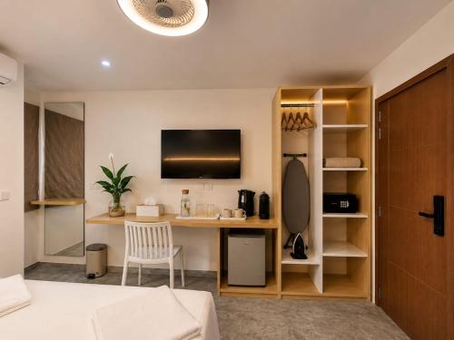 a bedroom with a desk and a tv on a wall at Veli Beach Inn in Mathiveri