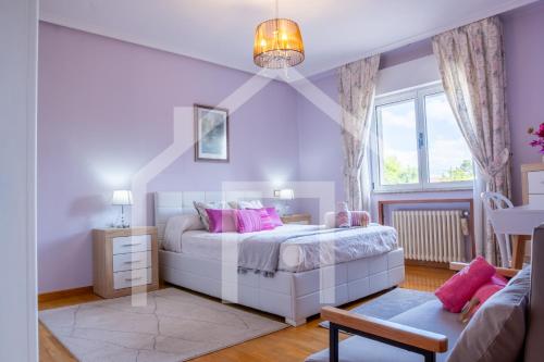 a bedroom with a white bed and pink pillows at El Jardin de Pruvia in Llanera