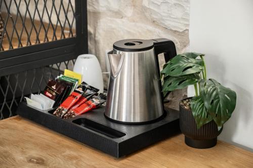 a tea kettle on a black tray next to a plant at City Port Hotel by Sea N Rent in Haifa