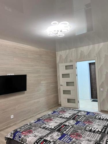 a bedroom with a bed and a flat screen tv at Дім Гаваї in Chechelivka
