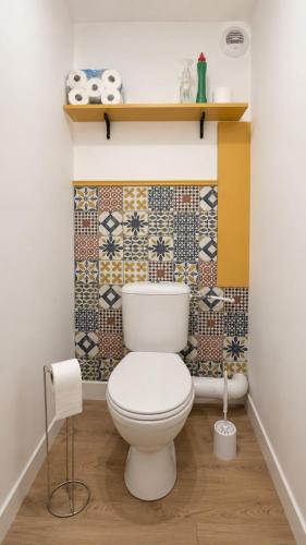 a bathroom with a toilet and a tile wall at Maison 8 personnes avec terrasse in Verdun