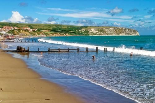 a group of people in the water at the beach at Dizzy Lows Modern 1 Bedroom Swanage Apartment with Sea View in Swanage