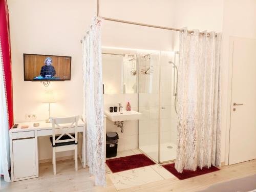 a bathroom with a shower and a sink and a desk at Pension am Wienfluss in Vienna
