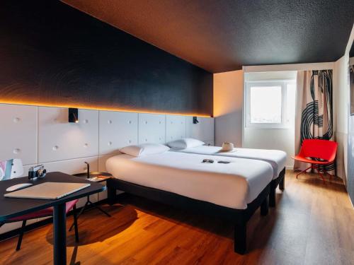 a bedroom with a large bed and a red chair at ibis Styles Lyon Sud Vienne in Chasse-sur-Rhône