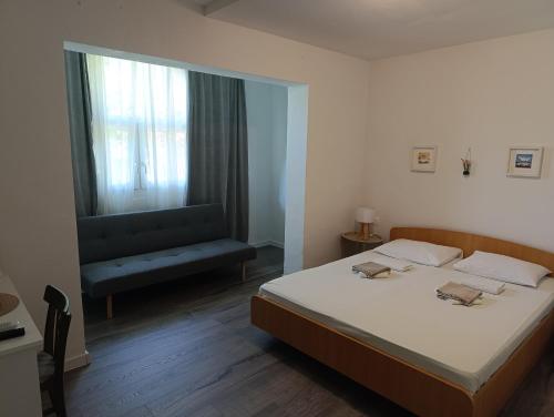 a bedroom with a bed and a window and a chair at Borovik Guest House in Živogošće