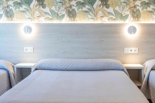 a bedroom with two beds and a floral wallpaper at Hotel Leal - La Sirena in Villanueva de Arosa