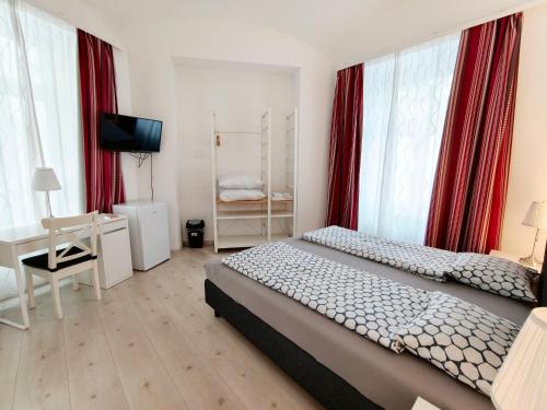 a bedroom with two beds and a desk and red curtains at Pension am Wienfluss in Vienna