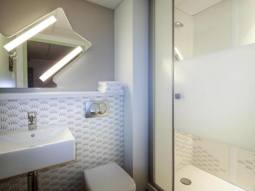 a bathroom with a sink and a toilet and a mirror at ibis budget Cahors in Cahors