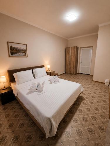 a bedroom with a large white bed with flowers on it at Dreamers Hostel & Hotel Apartment in Yerevan