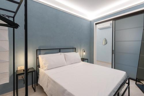 a bedroom with a white bed and a blue wall at Parmenide Family Apartment in Ascea