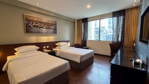 ein Hotelzimmer mit zwei Betten und einem Schreibtisch in der Unterkunft Hotel Royal Singapore in Singapur