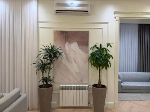a living room with two potted plants and a painting at Casa de prime in Baku