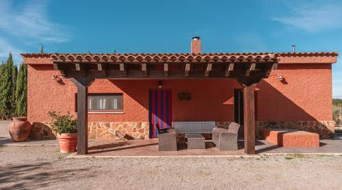 a red brick house with awning and chairs in front of it at Bodega Andrés Iniesta con visita y cata in Fuentealbilla