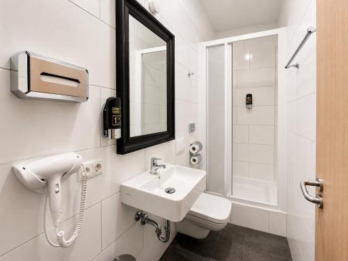 a white bathroom with a sink and a mirror at Nivara Hotel in Hamburg