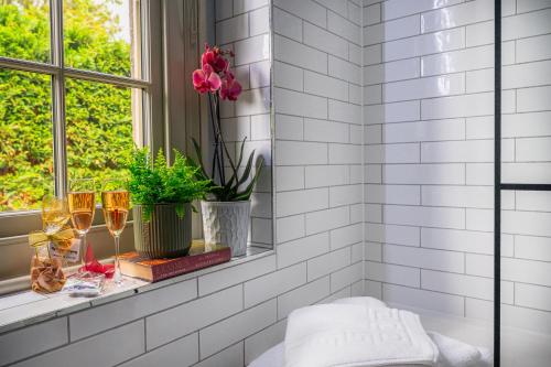 a white tiled bathroom with a window and two wine glasses at Crown & Punchbowl in Cambridge