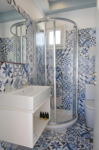 a bathroom with a sink and a shower with blue and white tiles at Avra Pension in Ios Chora