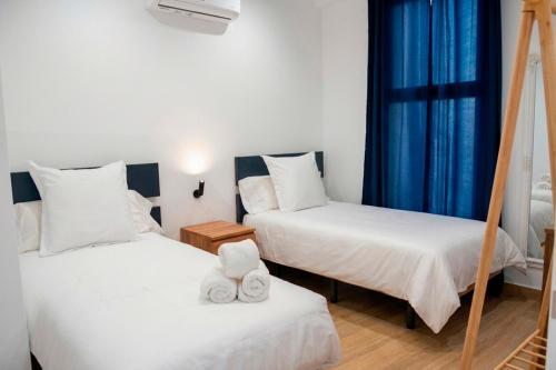 two beds in a room with blue curtains at Apartamento Menacho in Badajoz