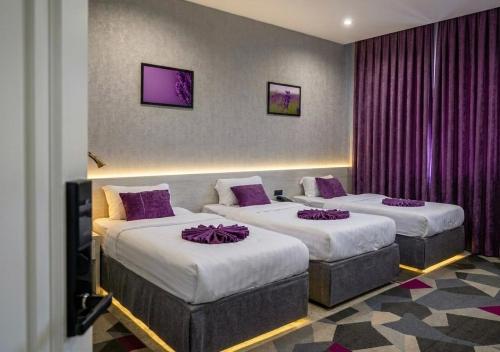 two beds in a hotel room with purple curtains at Lavanda hotel Tashkent in Tashkent