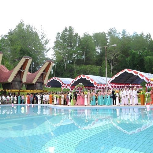 a group of people dressed in costumes standing around a swimming pool at Hotel Sahid Toraja in Makale
