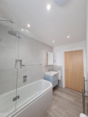 a white bathroom with a tub and a sink at Double room in a shared 2bed flat in Milton