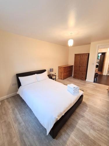 a bedroom with a large white bed and a wooden floor at Double room in a shared 2bed flat in Milton
