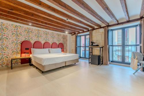 a bedroom with a large bed with a red headboard at Hotel Boutique Porta Ferrisa in Alicante