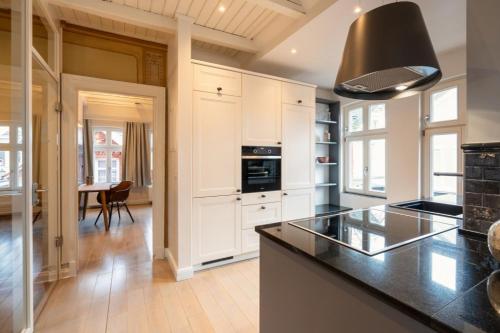 a kitchen with white cabinets and a black counter top at Commandeur-Huus Wohnung 3 in Borkum